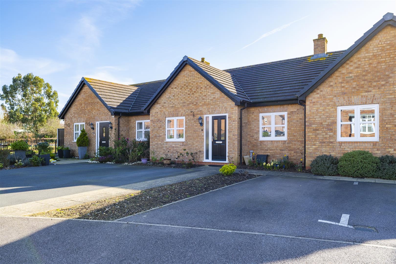 Brick house with driveway and garden shrubs.